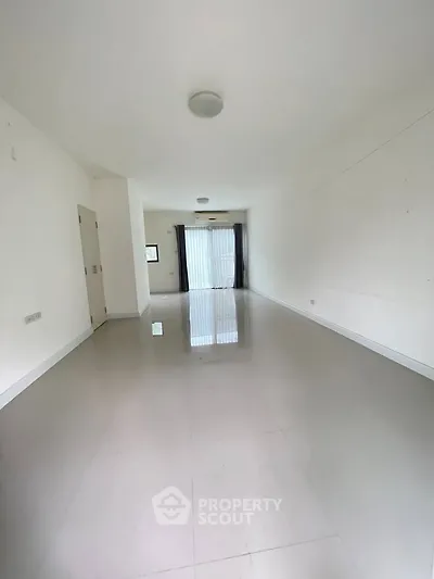 Spacious empty living room with glossy tiled floors and large window.