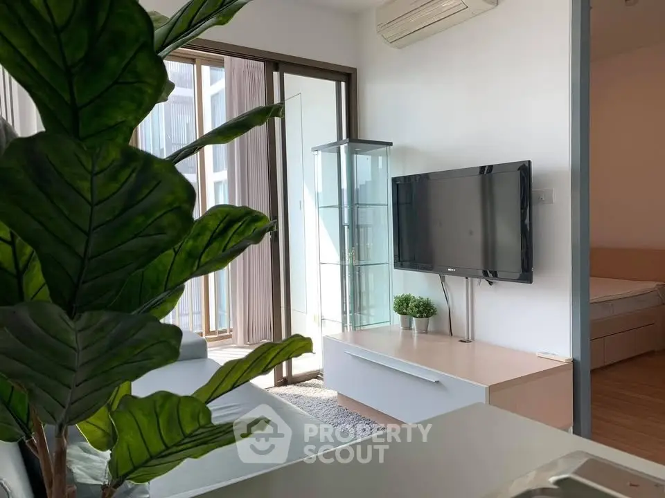 Modern living room with balcony access, featuring a wall-mounted TV and stylish decor.