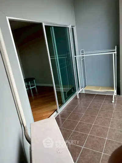 Spacious balcony with sliding glass doors and tiled flooring, perfect for relaxation or storage.