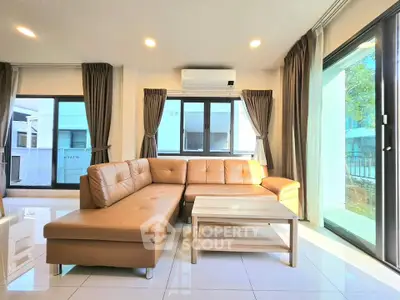 Spacious living room with modern leather sofa and large windows for natural light.