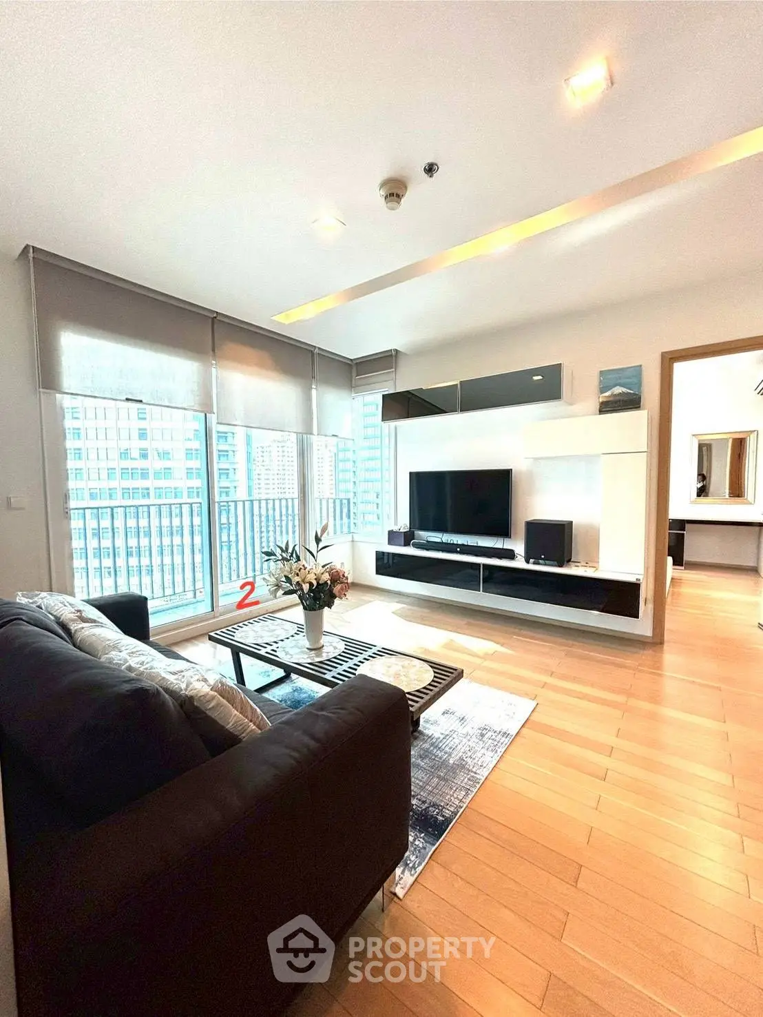 Spacious modern living room with large windows and stylish decor in a high-rise apartment.