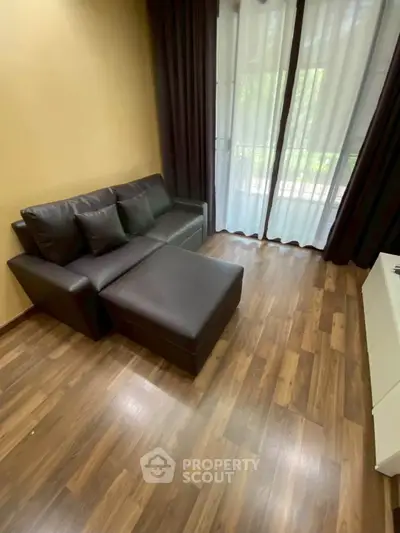 Cozy living room with modern brown leather sofa and wooden flooring, perfect for relaxation.