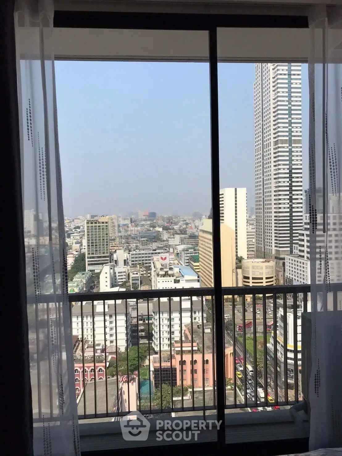 Stunning cityscape view from high-rise apartment balcony with floor-to-ceiling windows.