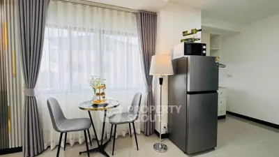 Modern kitchen with dining set and refrigerator, bright and airy ambiance.