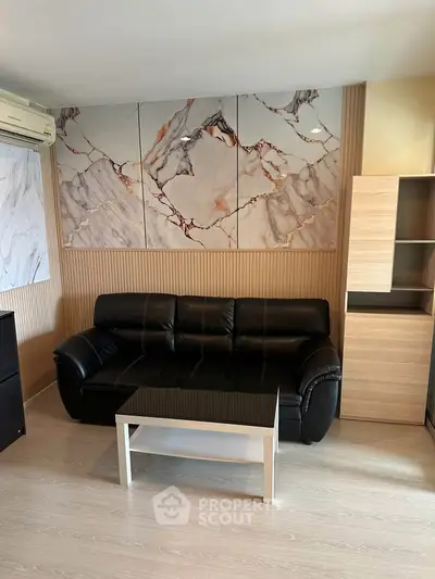 Modern living room with stylish marble wall art and black leather sofa, perfect for contemporary urban living.