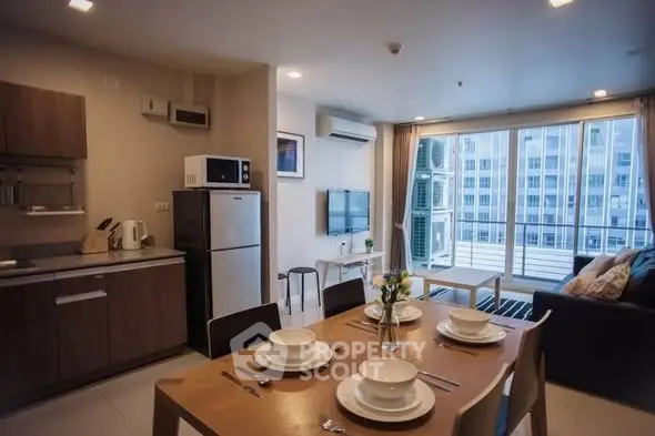 Modern open-plan living room and kitchen with balcony view in urban apartment.