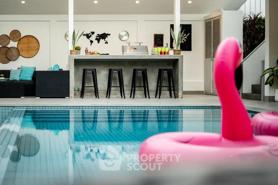 Luxurious poolside bar with modern seating and vibrant flamingo float, perfect for entertaining.