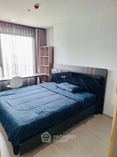 Modern bedroom with stylish bed and study area, featuring large window and natural light.