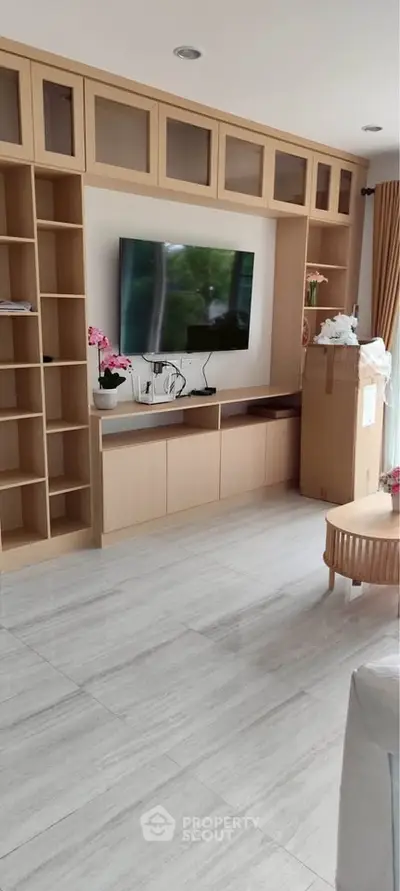 Modern living room with built-in shelves and large TV, perfect for entertainment and relaxation.