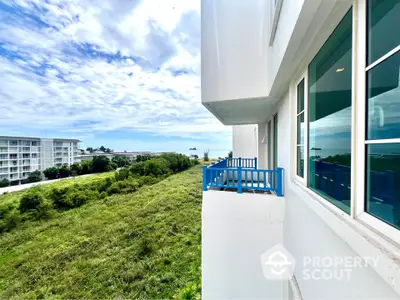 Modern apartment building with blue balconies and scenic green view.