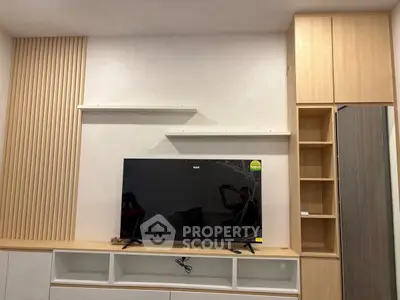 Modern living room with sleek TV setup and stylish wooden shelving.