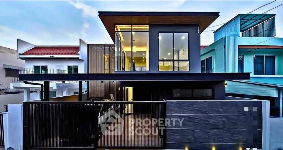 Modern two-story house with sleek design and large glass windows, featuring a stylish facade and contemporary architecture.