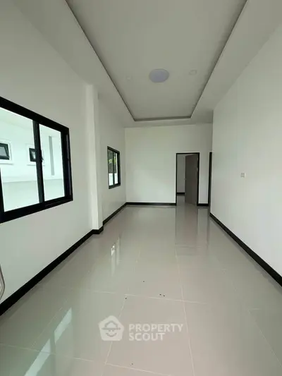 Spacious modern room with sleek tile flooring and large windows for natural light.