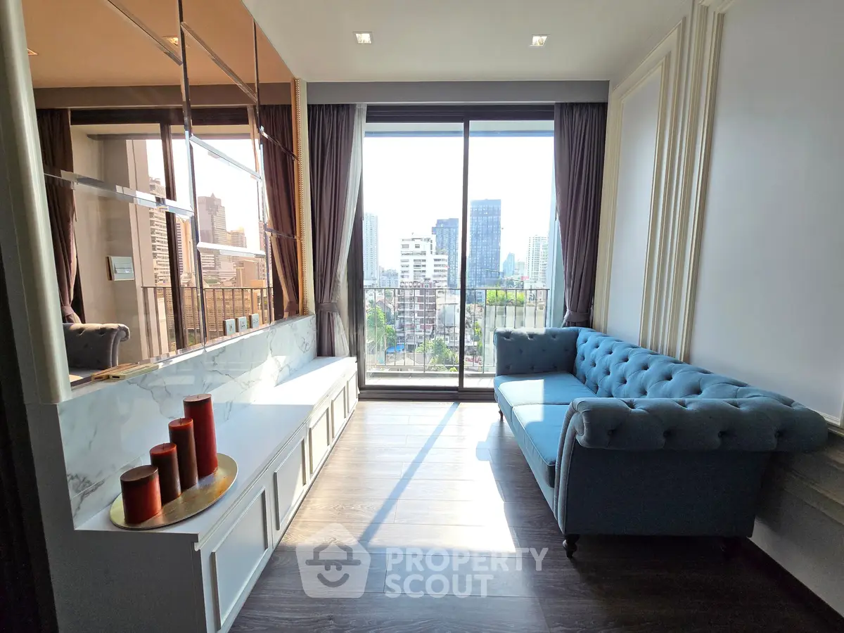 Stylish living room with large windows and city view, featuring a blue sofa and elegant decor.