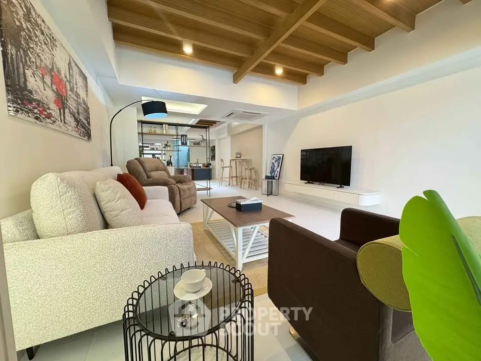 Spacious modern living room with stylish decor and wooden ceiling beams.
