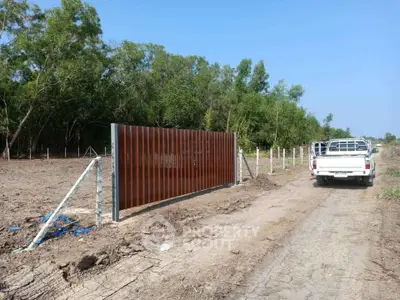 Expansive land plot with modern gate and rural road access, ideal for development opportunities.