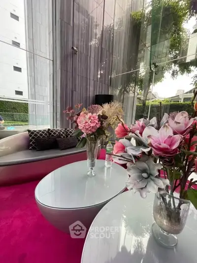 Luxurious modern living room with vibrant pink carpet and elegant floral decor, featuring floor-to-ceiling windows.