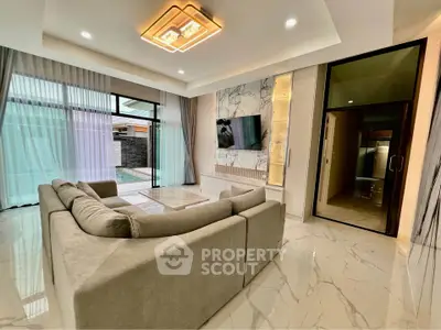 Luxurious modern living room with elegant marble flooring and stylish lighting, overlooking a serene pool area.