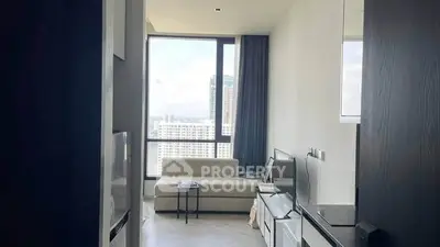 Modern living room with large window and city view, featuring sleek furniture and neutral tones.