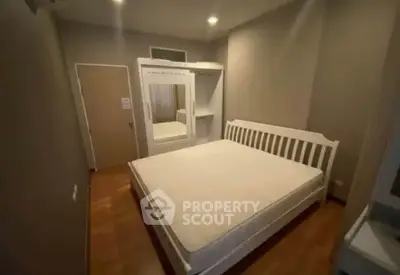 Cozy bedroom with wooden flooring and white furniture, perfect for relaxation.