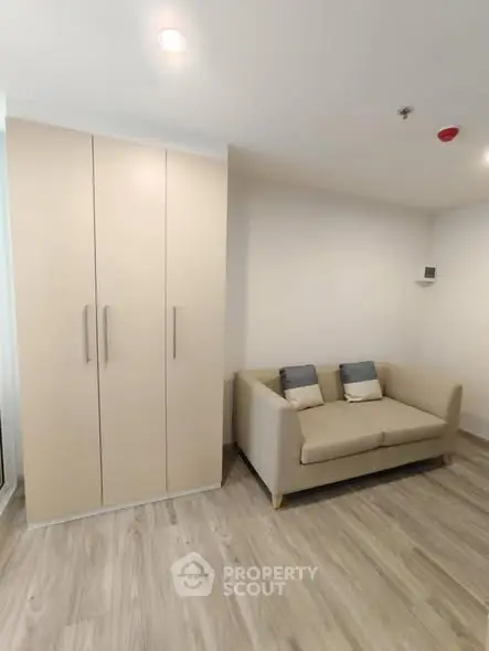 Modern living room with beige sofa and built-in wardrobe on wooden flooring.