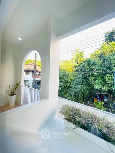 Charming balcony with lush greenery and street view, perfect for relaxation.