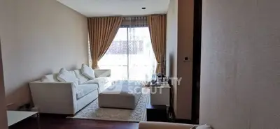 Cozy living room with elegant white sofa and large window with curtains.