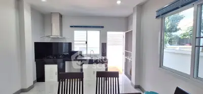 Modern kitchen with sleek black countertops and dining area, featuring natural light and open layout.