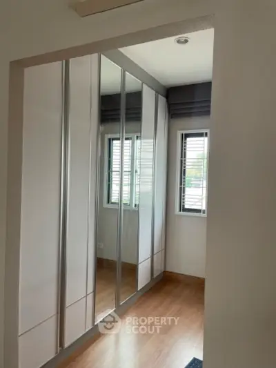 Spacious walk-in closet with mirrored sliding doors and natural light