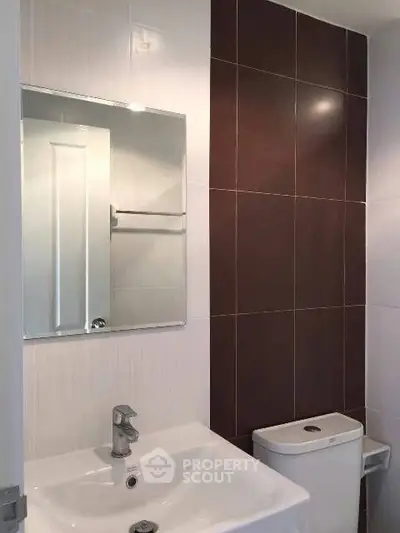 Modern bathroom with sleek sink and stylish brown tile accent wall.