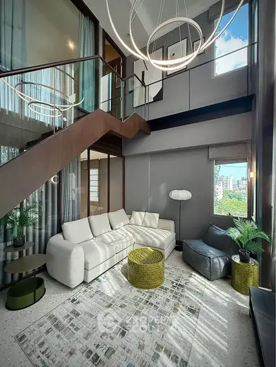 Luxurious modern living room with high ceilings, stylish furniture, and large windows offering city views.