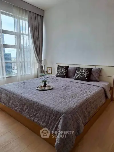 Spacious bedroom with large window and city view, featuring modern decor and cozy bedding.
