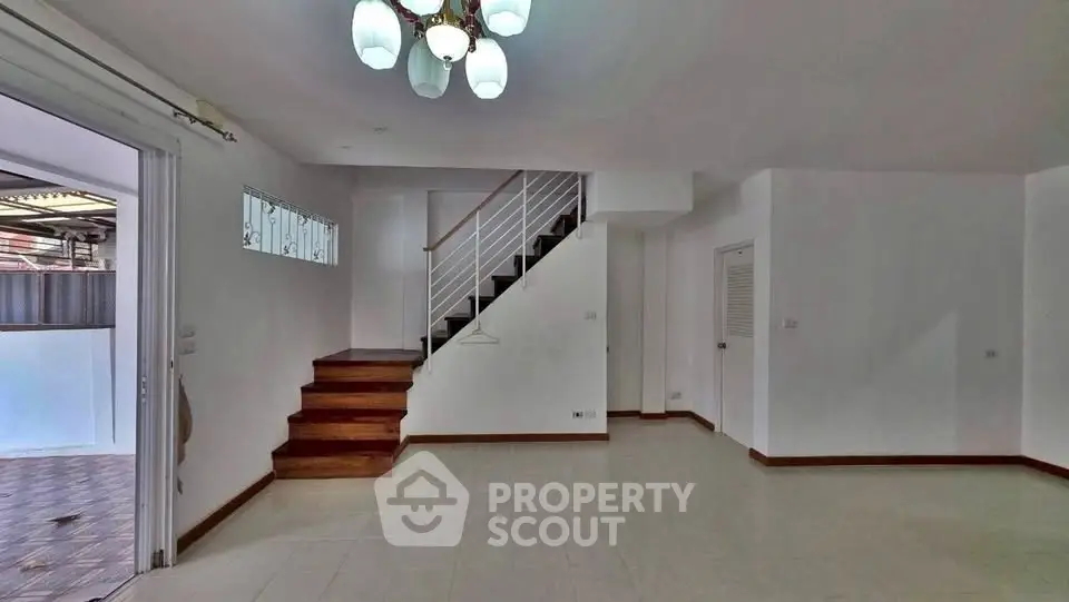 Spacious modern living room with staircase and elegant lighting in a contemporary home.