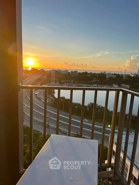 Stunning sunset view from a high-rise balcony overlooking a serene cityscape and highway.