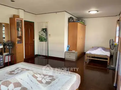 Spacious bedroom with wooden flooring and cozy decor