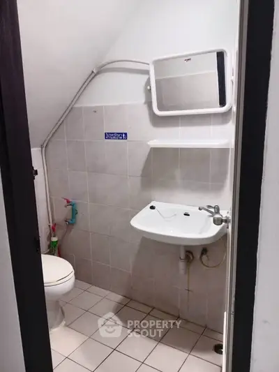 Compact bathroom with white tiles and basic fixtures, ideal for small spaces.