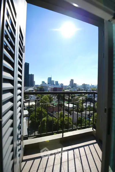 Stunning cityscape view from a modern balcony with open shutters and bright sunlight.