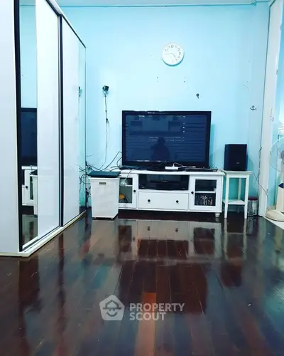 Spacious living room with polished wooden floors and modern entertainment setup.