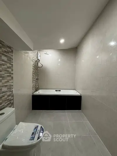 Modern bathroom with sleek tiles and built-in bathtub in a contemporary apartment.