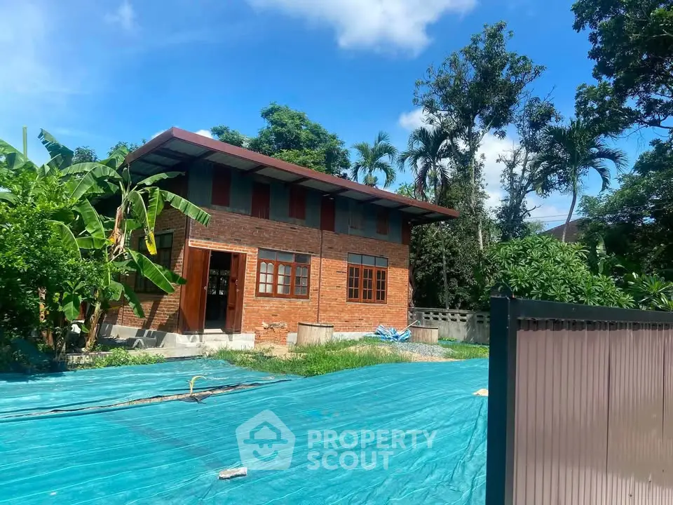 Charming brick house with lush garden and blue sky backdrop, perfect for serene living.