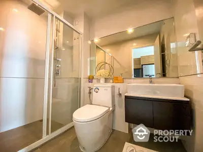 Modern bathroom with sleek glass shower enclosure, stylish vanity, and well-lit mirror creating a luxurious and inviting space.