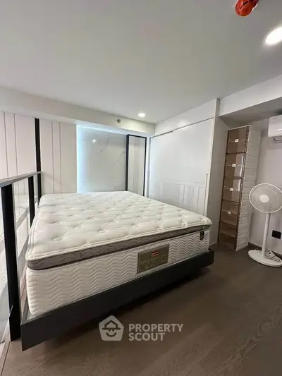 Modern bedroom with large mattress and sleek design, featuring wooden flooring and ample natural light.