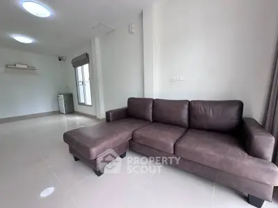 Spacious living room with modern brown leather sofa and natural light