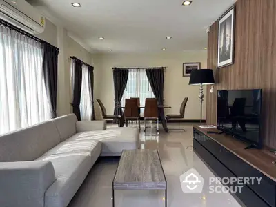 Modern living room with sleek furniture and dining area, featuring large windows and stylish decor.