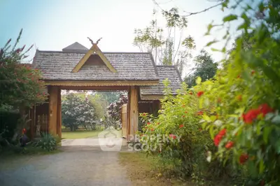 Charming rustic entrance to a serene garden property with lush greenery and traditional wooden architecture.