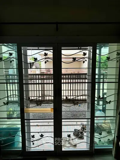 Spacious balcony with decorative metal doors and outdoor view, perfect for relaxation.