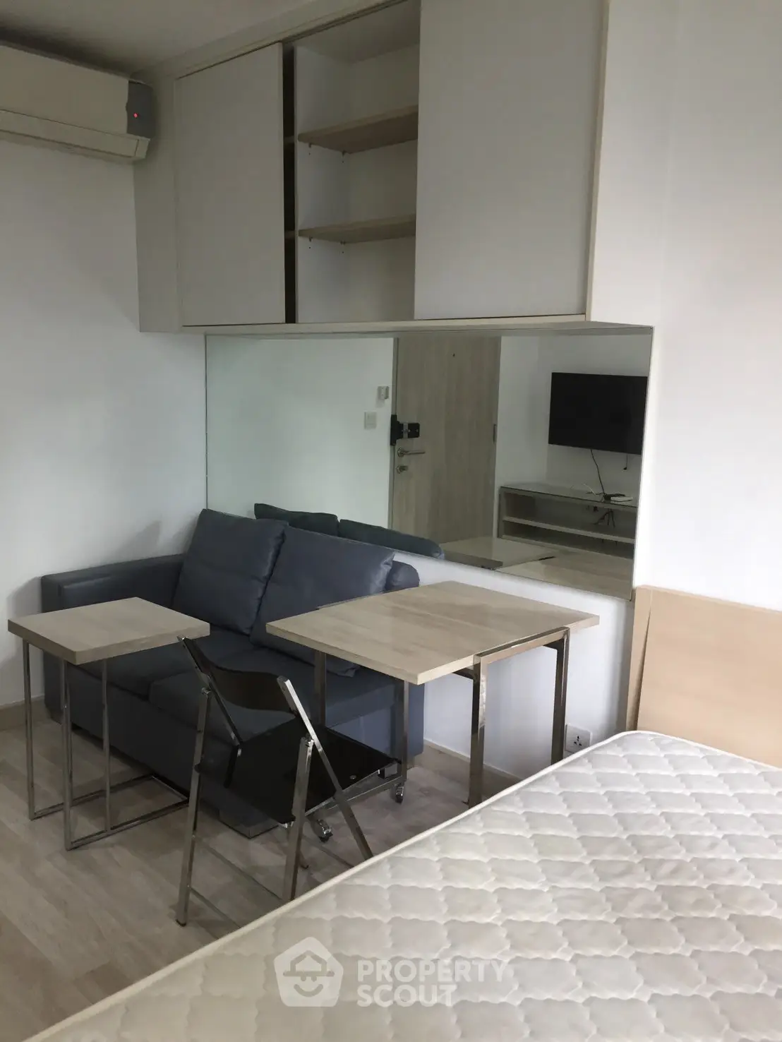 Modern compact studio apartment with sofa, bed, and wall-mounted TV, ideal for urban living.