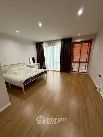 Spacious bedroom with modern decor and large windows for natural light