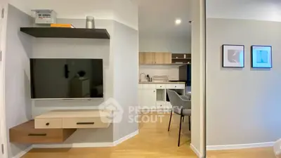 Modern living room with wall-mounted TV and view into stylish kitchen