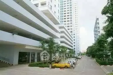 Modern residential building exterior with parking and lush greenery.